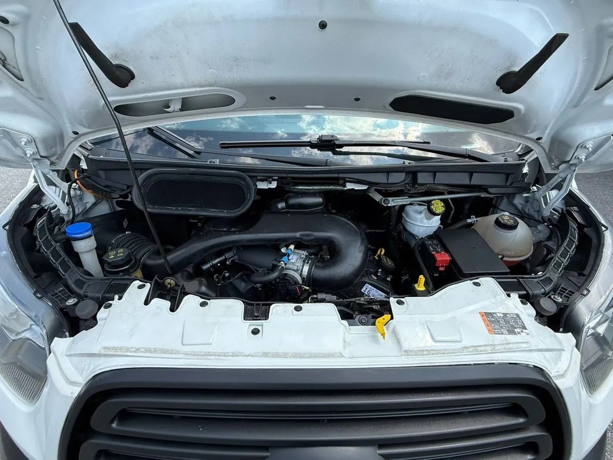 The engine bay of a Ford Transit van with the hood raised, showing the air intake, fluid reservoirs and fuse box