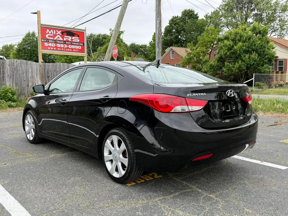 A black Hyundai Elantra sedan on the Mix Cars lot in Fredericksburg, with the red Mix Cars sign behind it