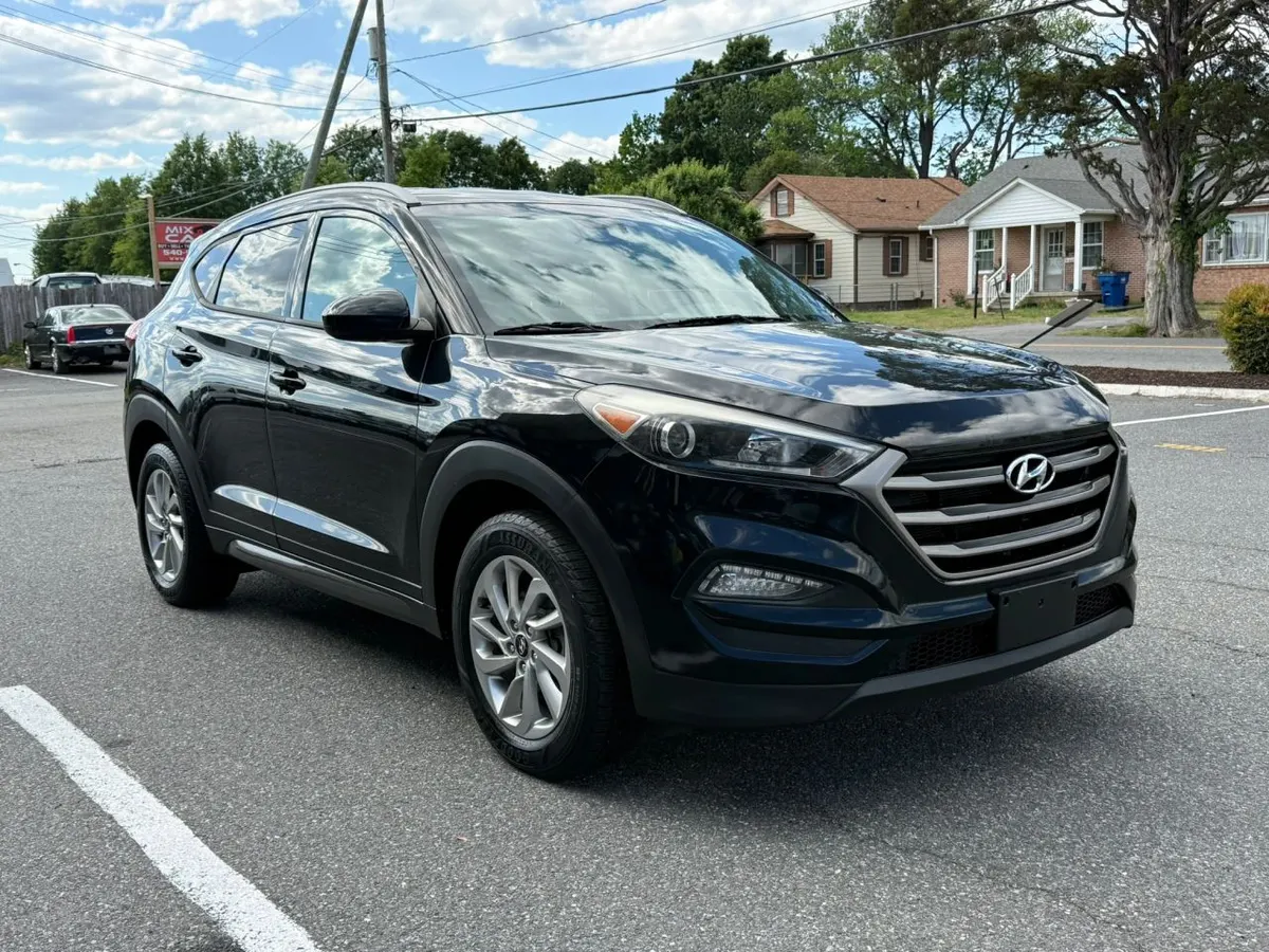 A black Hyundai Tucson SUV parked on the Mix Cars lot, with part of the Mix Cars sign in the background