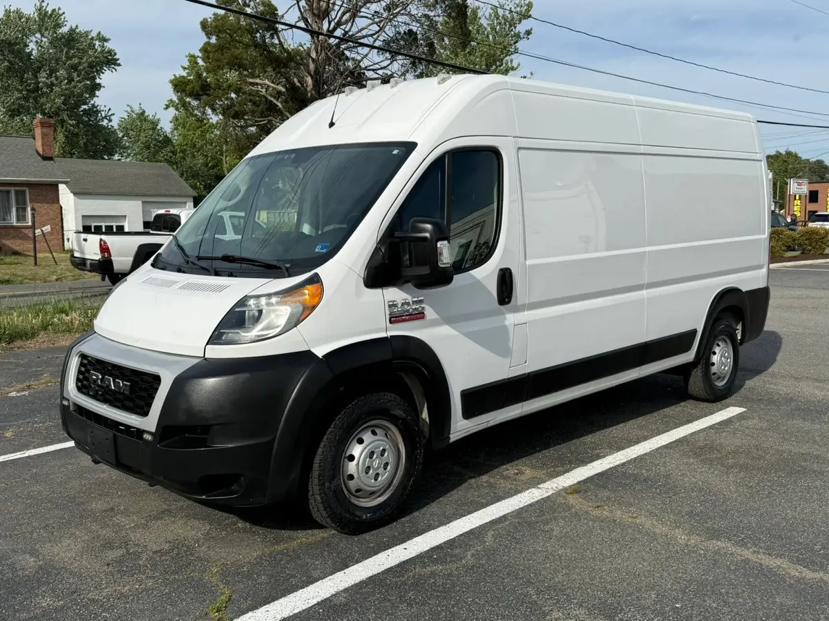 A white RAM ProMaster high-roof cargo van parked on the Mix Cars lot, seen from the front driver's side