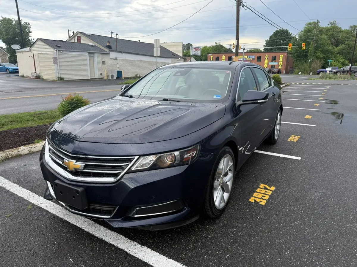 A dark blue Chevrolet Impala sedan parked in a marked space on the Mix Cars lot after rain