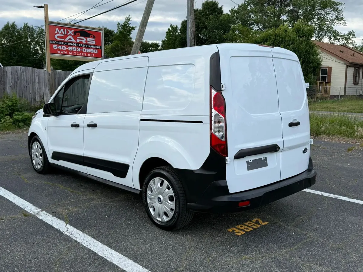 A white Ford Transit Connect cargo van on the Mix Cars lot, with the Mix Cars sign reading Buy, Sell, Trade, Easy Financing behind it