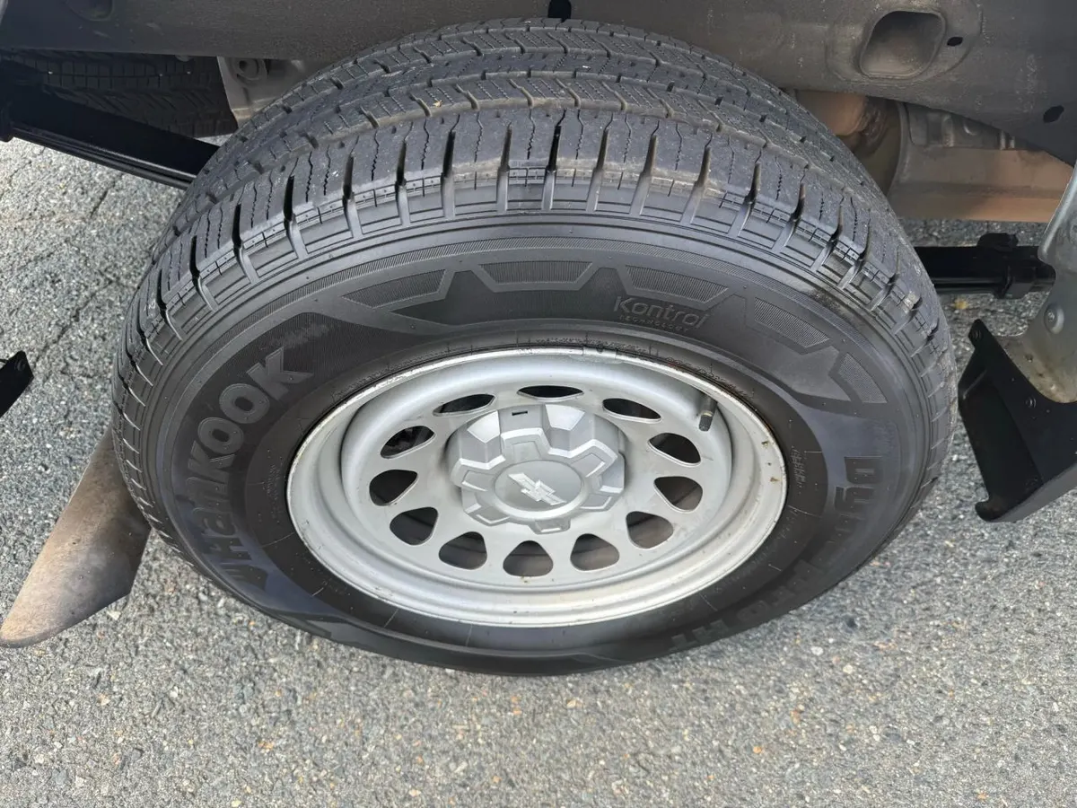 A pickup truck tire on a steel wheel, showing the tread blocks and part of the truck's underside