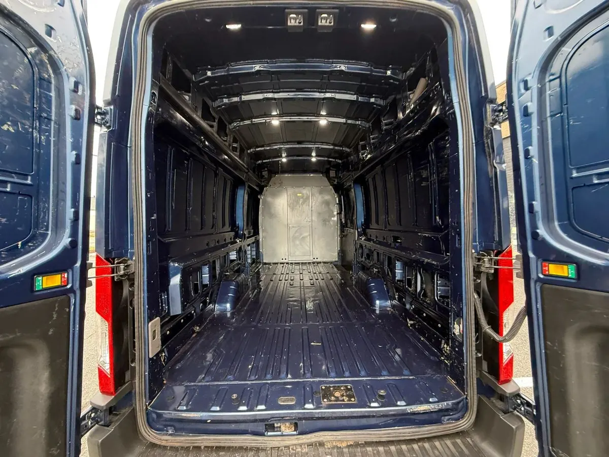 The empty cargo area of a blue Ford Transit extended-length high-roof van seen through its open rear doors