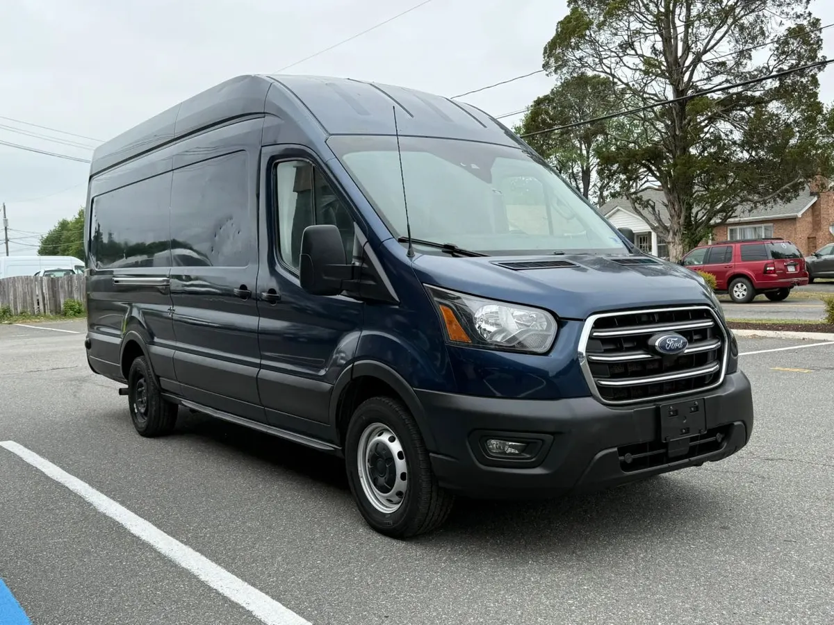 A blue Ford Transit high-roof cargo van parked on the Mix Cars lot, seen from the front passenger side