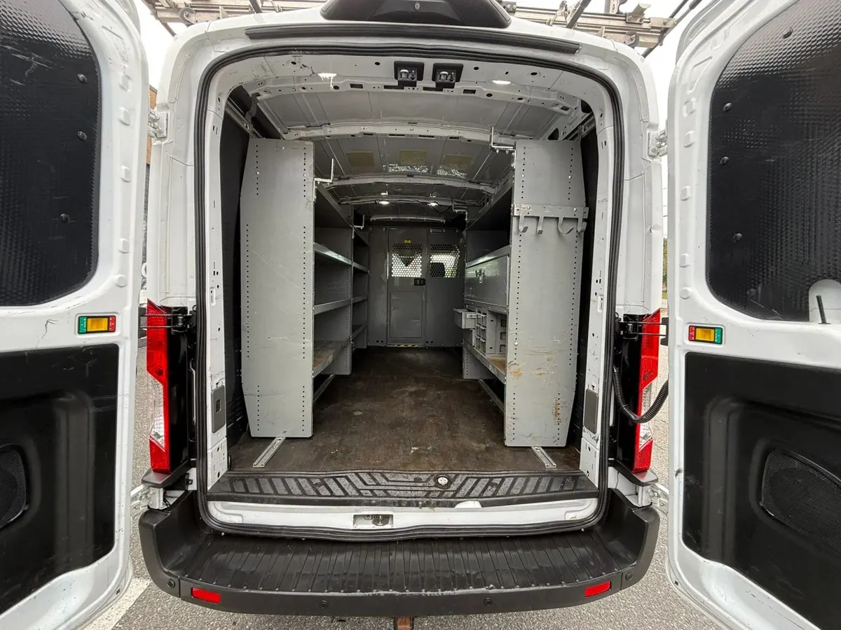 Steel shelving units along both walls of a Ford Transit cargo area, seen through the open rear doors
