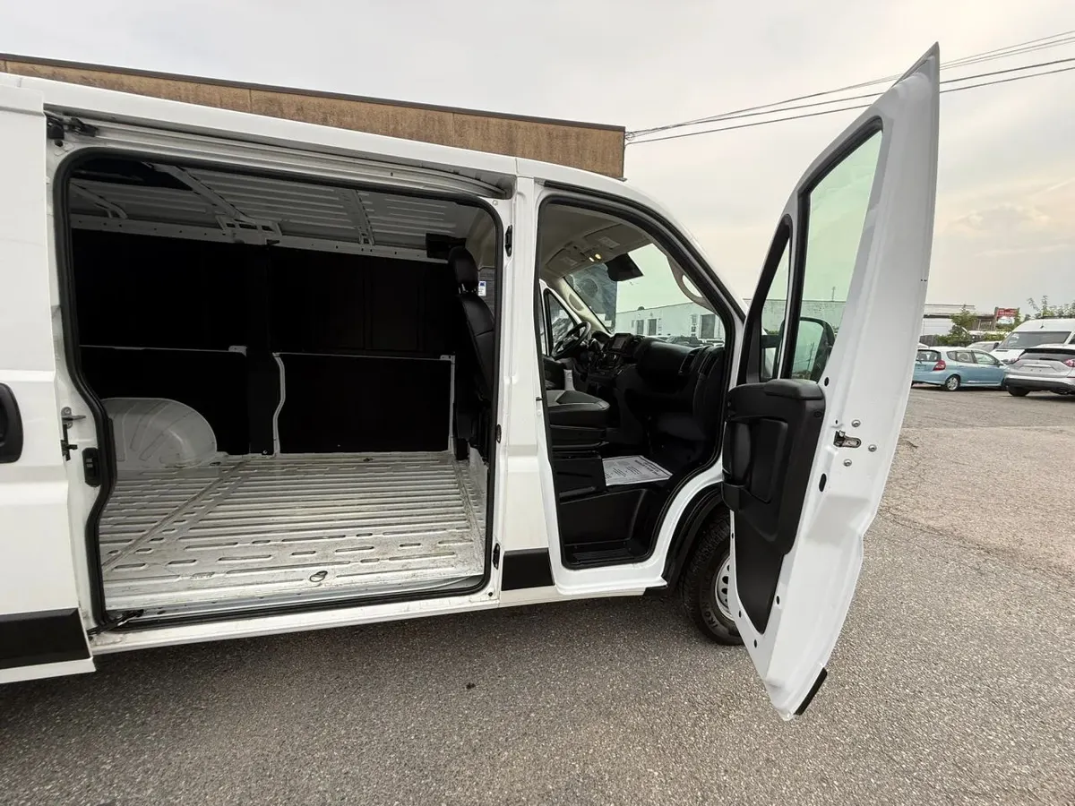 A RAM ProMaster cargo van with the sliding side door and the front door open, showing the empty cargo floor