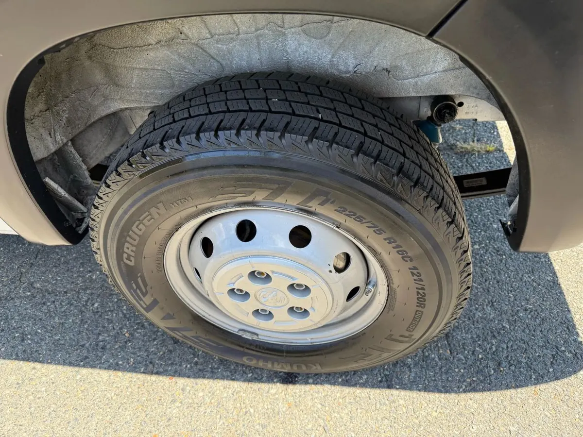 A cargo van tire inside its wheel well, with the size 225/75 R16C printed on the sidewall